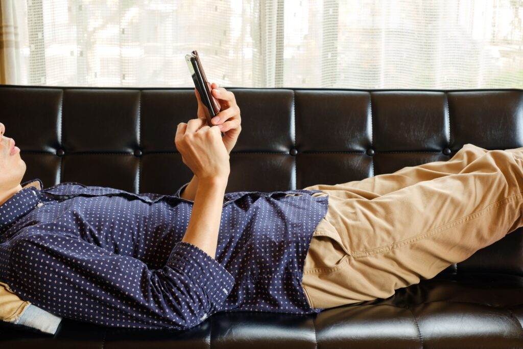 スマホを見ながらだらける男性